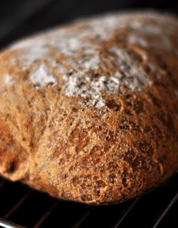 A loaf of Olandshvedebrod resting on a cooling rack, showcasing its golden crust and inviting texture